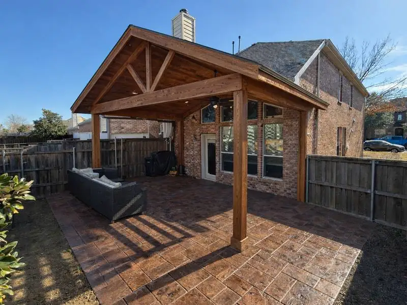 Cedar pergola over a stamped concrete patio with a round pool